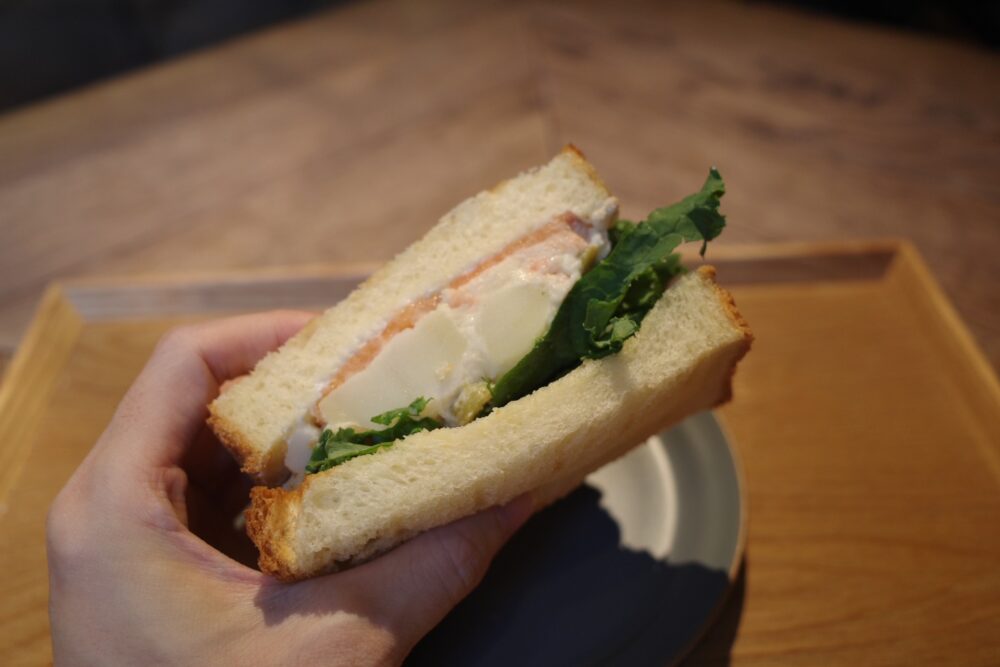 一口のサーモンとポテトサラダのサンドイッチ